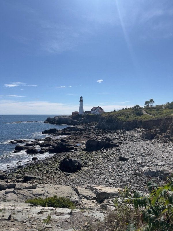 A lighthouse on a rocky coastline under a clear blue sky