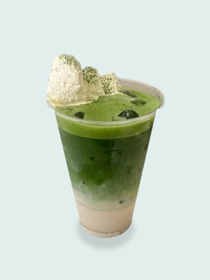 An iced matcha latte topped with whipped cream and matcha powder