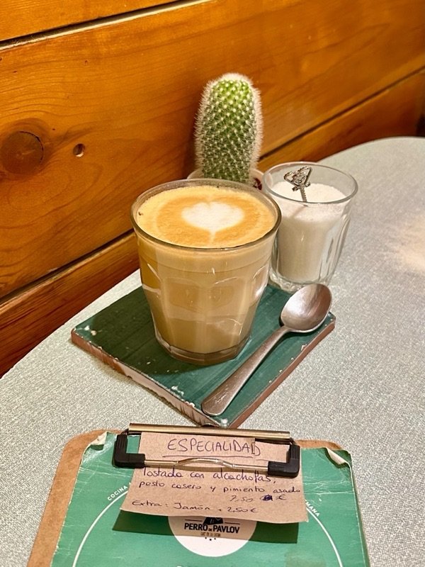 A latte with heart latte art next to a small cactus, photographed at a café while traveling